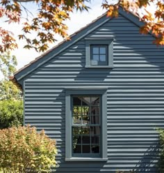 a blue house with an open window in the front yard and trees around it,