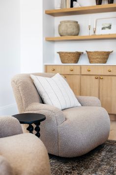 a living room filled with furniture next to a wall mounted book shelf and wooden shelves