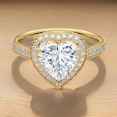 a heart shaped diamond ring with diamonds on the band and side stones set in 18k yellow gold