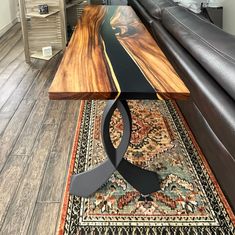 a wooden table sitting on top of a rug next to a black leather couch in a living room