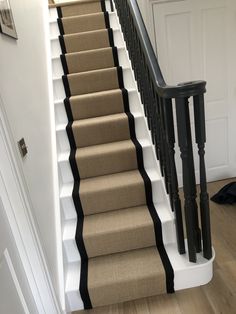 there is a set of stairs with black handrails and beige carpet on the bottom