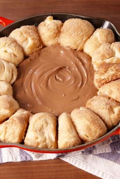 a pan filled with cookies and peanut butter on top of a wooden table next to a white towel