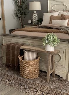 a white bed sitting next to a wooden table with a potted plant on top of it