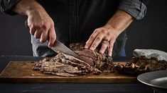 a man cutting up some meat on top of a wooden cutting board with a knife