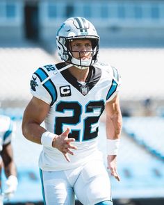 a football player wearing a helmet and holding a ball in his hand while walking on the field