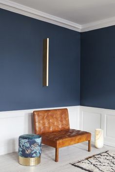 a living room with blue walls and leather chair in the corner next to a rug