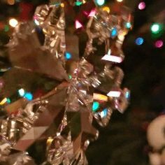 a snowflake ornament is shown in front of a christmas tree with lights