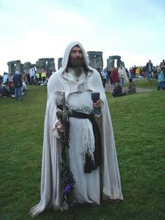 a man dressed up as jesus standing in the middle of a field with people around him