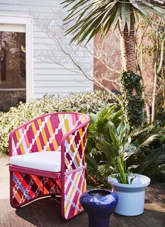 a pink chair sitting on top of a wooden table next to two potted plants