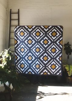 a large black and yellow quilt sitting on top of a floor next to a ladder