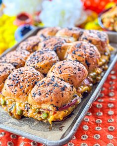 a tray filled with sandwiches sitting on top of a red table cloth next to other food items