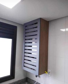 a bathroom with white tile and wooden cabinet next to a large window in the corner