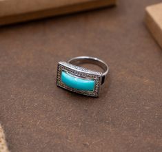 Embrace the allure of the Southwest with this 8.5-gram rectangular silver ring from Gemoholic, featuring a stunning turquoise centerpiece. The vibrant hues of the turquoise evoke the spirit of open skies and sprawling deserts, while the rectangular framing and dazzling white topaz accents add a contemporary touch to this timeless piece. Striking Turquoise: A rectangle-cut turquoise stone offers a bold splash of color and natural patterning. Shimmering Accents: The silver frame is meticulously st Rectangular Turquoise Rings For Anniversary, Rectangular Turquoise Ring For Anniversary, Anniversary Turquoise Rectangular Ring, Anniversary Rectangular Turquoise Ring, Rectangular Turquoise Gemstone Ring As Gift, Elegant Rectangular Turquoise Ring, Rectangular Turquoise Ring Gift, Handmade Silver Rectangular Turquoise Ring, Silver Rectangular Turquoise Gemstone Ring