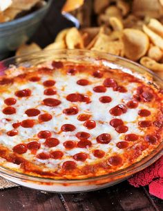 a pepperoni pizza sitting on top of a glass plate next to some pita chips