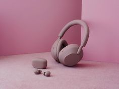 a pair of headphones sitting on top of a pink floor next to ear buds