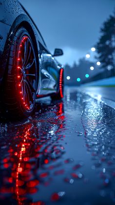 a close up of a car on a wet road with lights reflecting off the ground