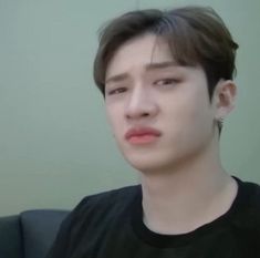 a young man with ear piercings on his ears looking off to the side while sitting in a chair