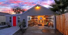 a house with a red door and palm tree in the front yard at sunset or dawn