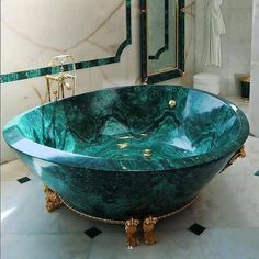 a large green marble bathtub sitting in a bathroom next to a sink and mirror