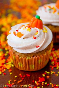 two cupcakes with white frosting and sprinkles on a table