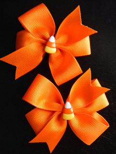 two orange bows with white dots on them sitting next to each other in front of a black background