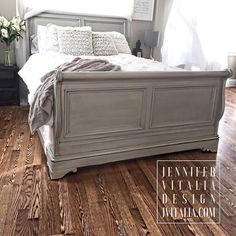 a white bed sitting on top of a hard wood floor next to a vase with flowers