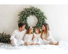 a family sitting in front of a christmas wreath