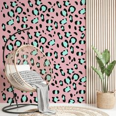 a room with pink and green leopard print wallpaper, a rattan chair and potted plant