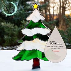 a christmas tree shaped glass ornament on top of a snow covered ground with trees in the background