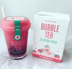 a pink bubble tea cup next to a box of strawberry flavored bubble tea on a bed