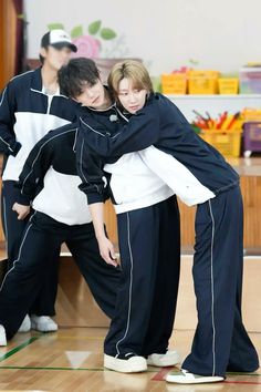 two young men are hugging each other on the dance floor in black and white tracksuits