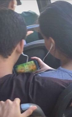 two people looking at their cell phones in the back seat of a car while one person is sitting down and listening to music