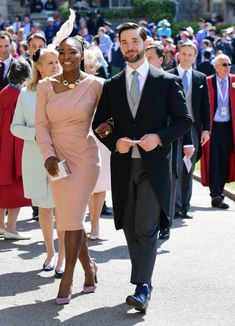 a man in a suit and tie walking next to a woman in a pink dress