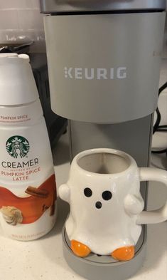 a starbucks coffee maker next to a ceramic mug