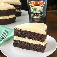 a piece of cake sitting on top of a white plate next to a bottle of bailey's