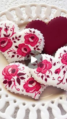 heart shaped cookies decorated with pink and red flowers on a white doily tablecloth