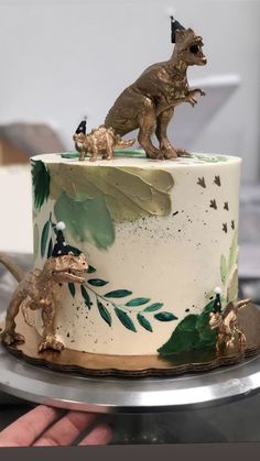 there is a cake decorated with dinosaurs and leaves on the top, along with other decorations