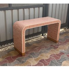 a bench sitting on top of a tiled floor next to a metal fence and wall