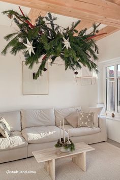 a living room filled with furniture and a christmas tree hanging from the ceiling above it