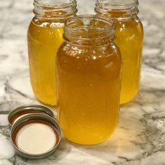 three jars filled with liquid sitting on top of a counter