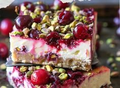 two pieces of cheesecake topped with cherries and pistachios