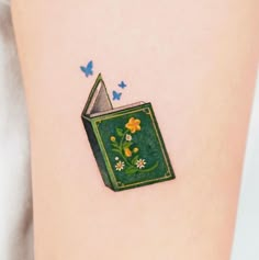 a book tattoo with flowers and butterflies on it