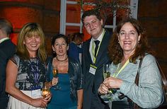 several people standing together holding wine glasses in their hands and smiling at the camera with smiles on their faces