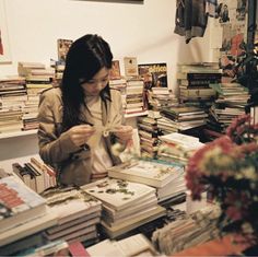 a woman standing in front of a table filled with books