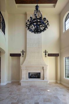 a chandelier hangs from the ceiling above a fireplace in a large living room