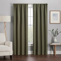 a living room filled with furniture and a window covered in green drapes, next to a white chair