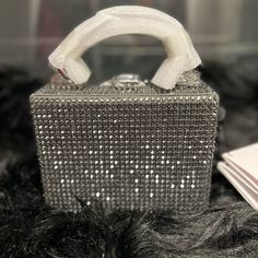 Color: Grey Dimensions: 5.8”W X 4.3”H X 3"D Handle Drop: 3" Shoulder Strap: 18”-22” Mini Handbag/ Cross-Body Bag Buckle-Clasp Fastening Hand-Sewn Double Stitched Handle Adjustable, Detachable, Leather, Cross-Body, Strap Dust Bag Included Imported Composition Material: Rhinestone, 100% Cowhide Leather, 100% Cotton Canvas Hardware: Silver Metalware Lining: Microsuede Item Care Do Not Machine Wash Do Not Bleach Do Not Tumble Dry Do Not Iron Do Not Dry Clean High-end Top Handle Box Bag For Party, Luxury Box Bag With Top Carry Handle For Party, Luxury Party Box Bag With Top Carry Handle, Luxury Silver Box Bag For Shopping, Luxury Silver Box Bag, Luxury Square Box Bag For Party, Luxury Silver Rectangular Box Bag, Luxury Silver Box Bag For Party, Designer Silver Box Bag For Evening