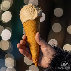 a person holding an ice cream cone in front of some boket lights at night