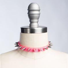 Classic choker collar with a colorful twist. Silver 1/2" spikes riveted evenly throughout. Adjustable buckle in back. Available in PVC, leather, or vegan leather. An essential item for any goth or punk who likes a little bit of color, festival or clubkids-inspired looks. Collar is 1/2" wide. Shown in neon pink PVC. Silver-toned nickle plated steel hardware. Neon pink and neon orange PVC are UV/Blacklight reactive. SMALL/MEDIUM (11-13")MEDIUM/LARGE (13-15")LARGE/X-LARGE (15-17") Custom sizing ava Gothic Spiked Choker For Festivals, Party Choker With Spikes, Adjustable Emo Choker For Cosplay, Trendy Pink Festival Choker, Punk Spikes Choker For Party, Punk Spiked Choker For Parties, Punk Choker For Halloween Festival, Adjustable Emo Choker For Concerts, Adjustable Emo Choker For Alternative Fashion