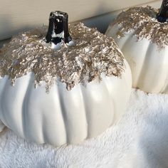 two white pumpkins with gold glitter on them